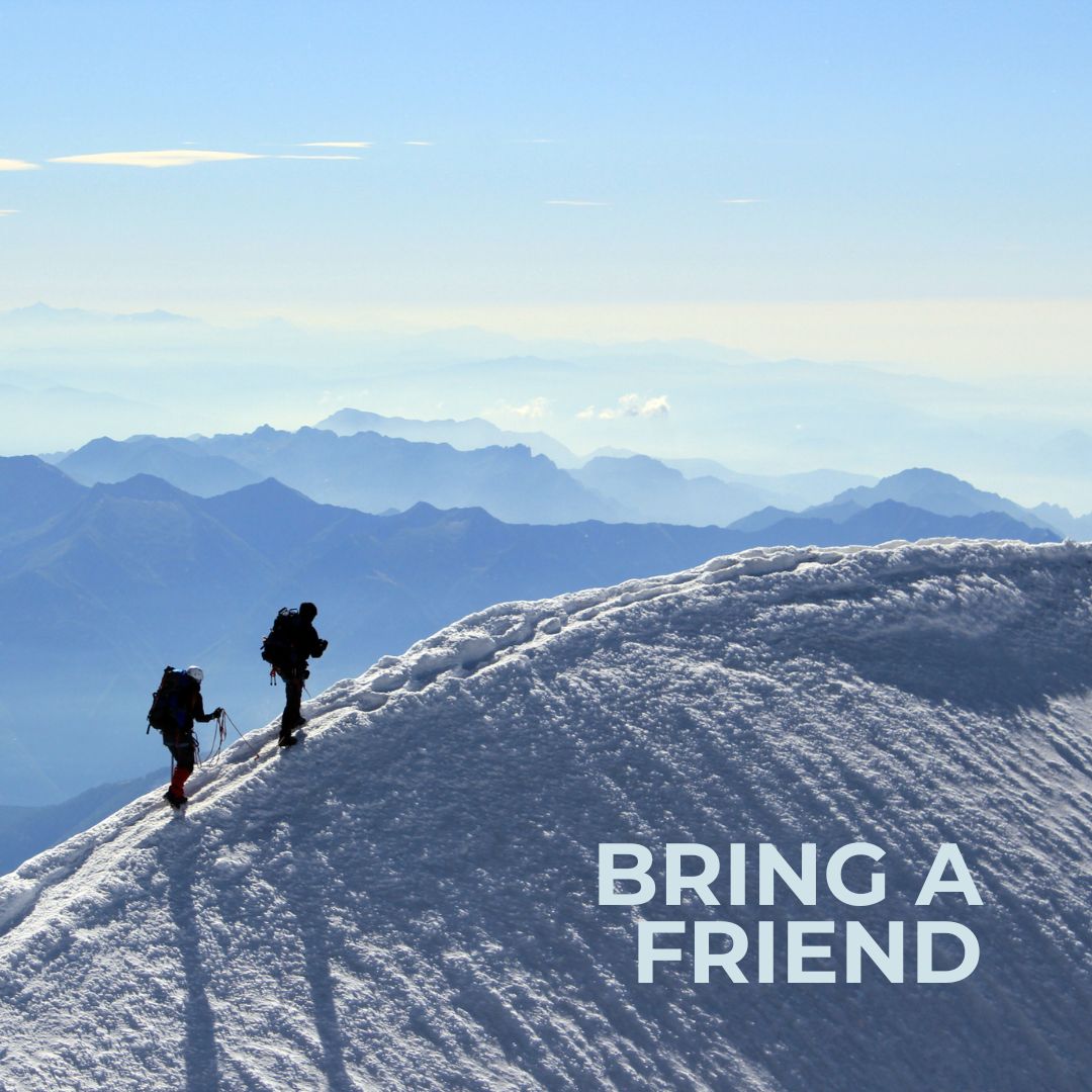 two people hiking the ridge line of a snowy peak