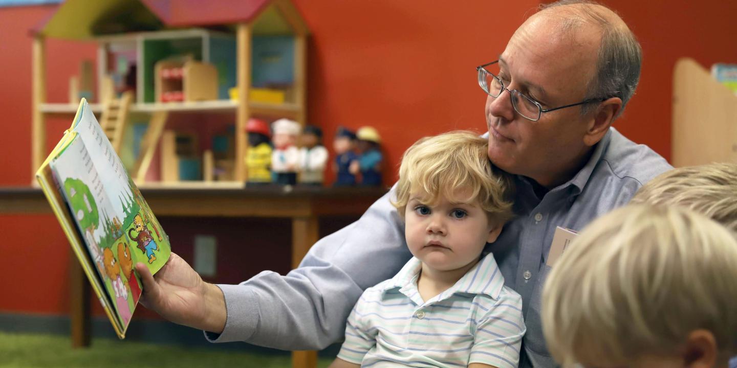 Preschool caregiver reading to young boy