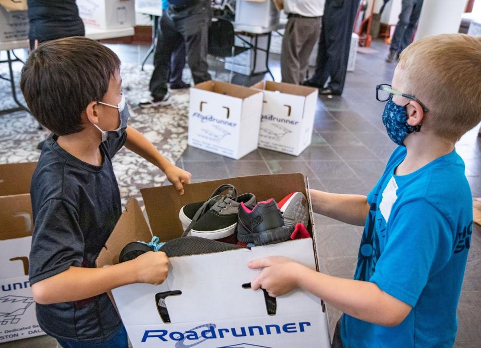 Children lifting boxes of donated shoes during the Henry Hill Memorial Shoe Drive